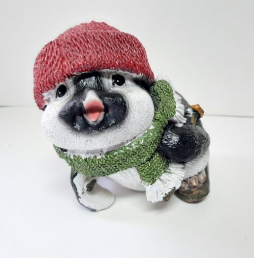 Beeldje pinguin op skis met rode muts en groene sjaal voorover