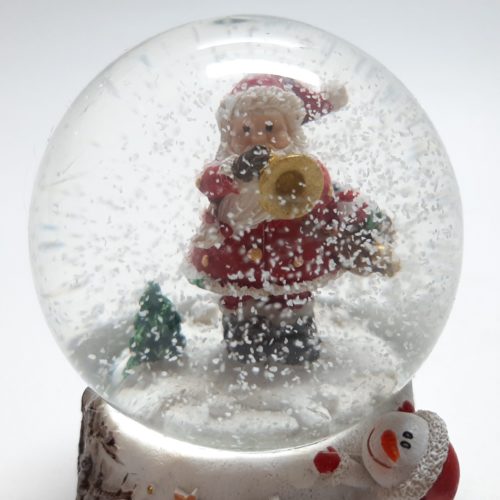 sneeuwbol witte basis sneeuwpop kijkt naar kerstman met trompet