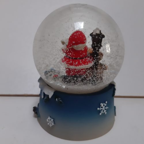 Sneeuwbol kerstman met zak cadeaus bij lantaarn op blauwe basis met arreslee