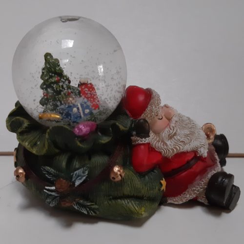Sneeuwbol slapende kerstman op groene zak in 3d met in de bol kerstboom en cadeaus 7cm hoog